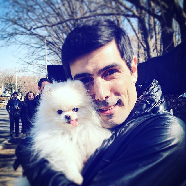 Louis Cancelmi in a black leather jacket holding his pretty pet dog.
